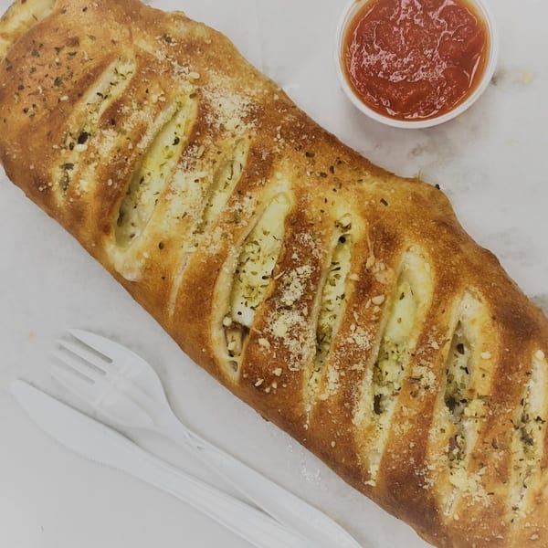 Gusto's Pizza stromboli with cheese and herbs, served with a side of marinara sauce and plastic cutlery.
