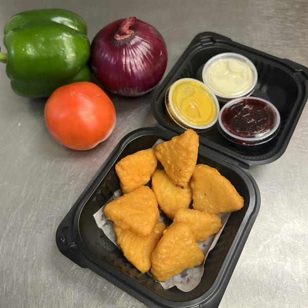 Fried cheese curds with dipping sauces, bell pepper, onion, and tomato on a metal counter.
