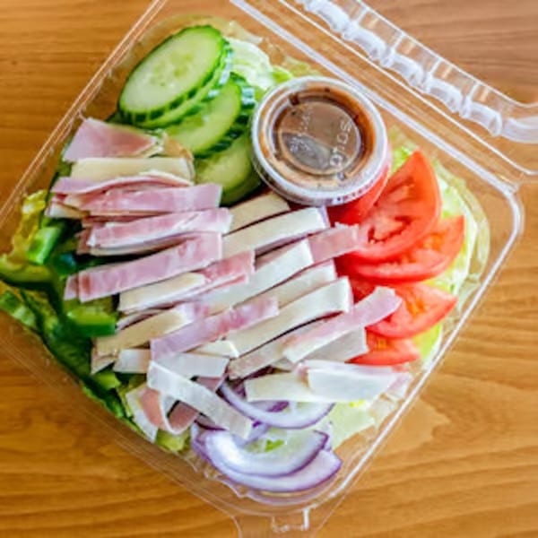 A Gusto's Pizza chef salad with ham, cheese, tomatoes, cucumbers, onions, and dressing in a plastic container.