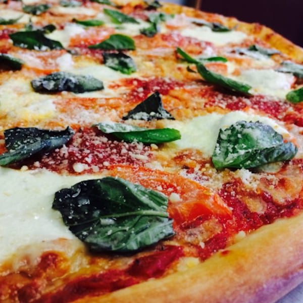 Close-up of a Gusto's Pizza Margherita, topped with fresh basil, mozzarella, and tomato sauce.